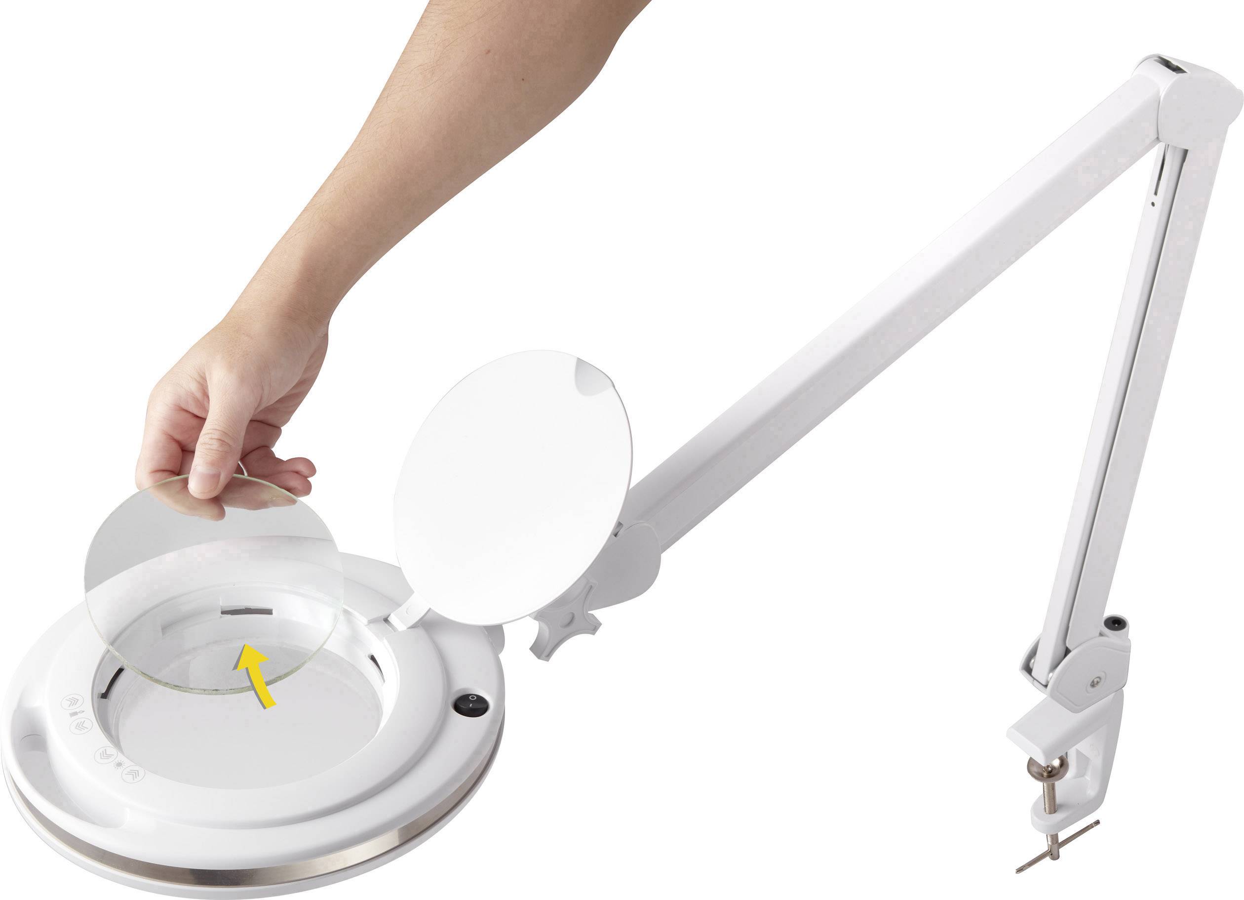 Arm einer Schreibtischlampe mit Lupe und Deckel. Eine Hand hebt den Deckel an, um das Glas zu reinigen oder zu ersetzen.