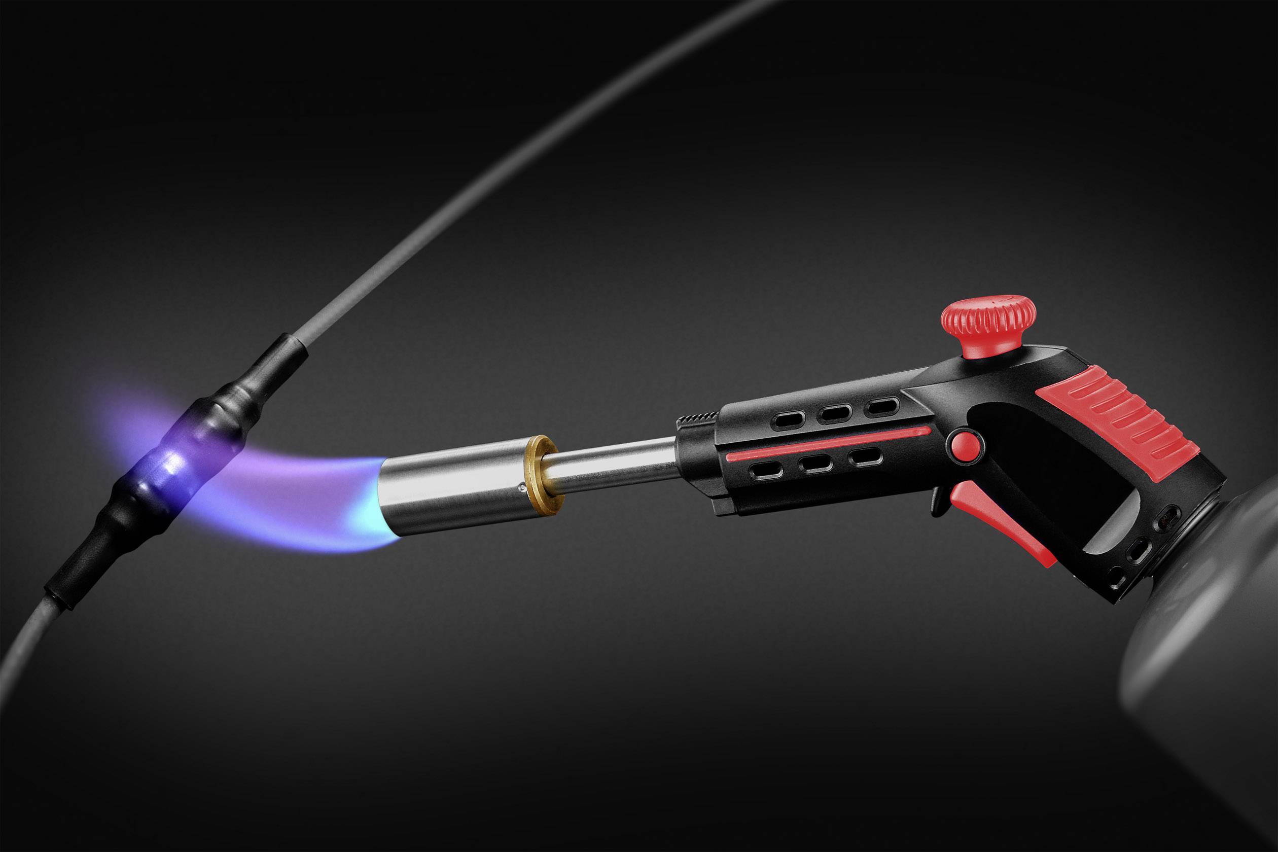 Ein Gasbrenner mit blauer Flamme erhitzt ein schwarzes Kabel in einer dunklen Umgebung, möglicherweise zur Reparatur oder Verbindung.
