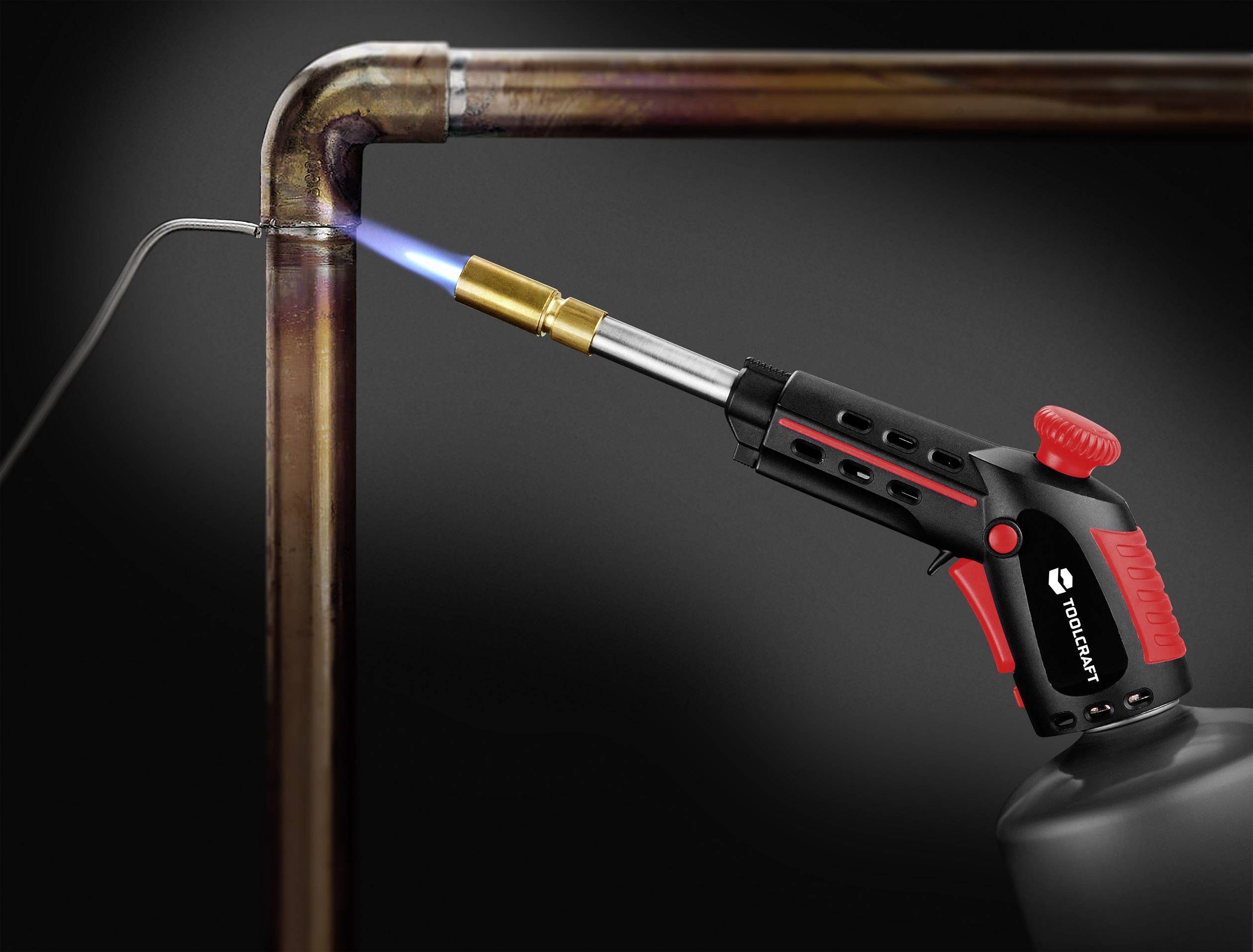 Eine Lötlampe erhitzt ein Kupferrohr, um eine Verbindung zu verschweißen. Die bläuliche Flamme ist klar sichtbar.