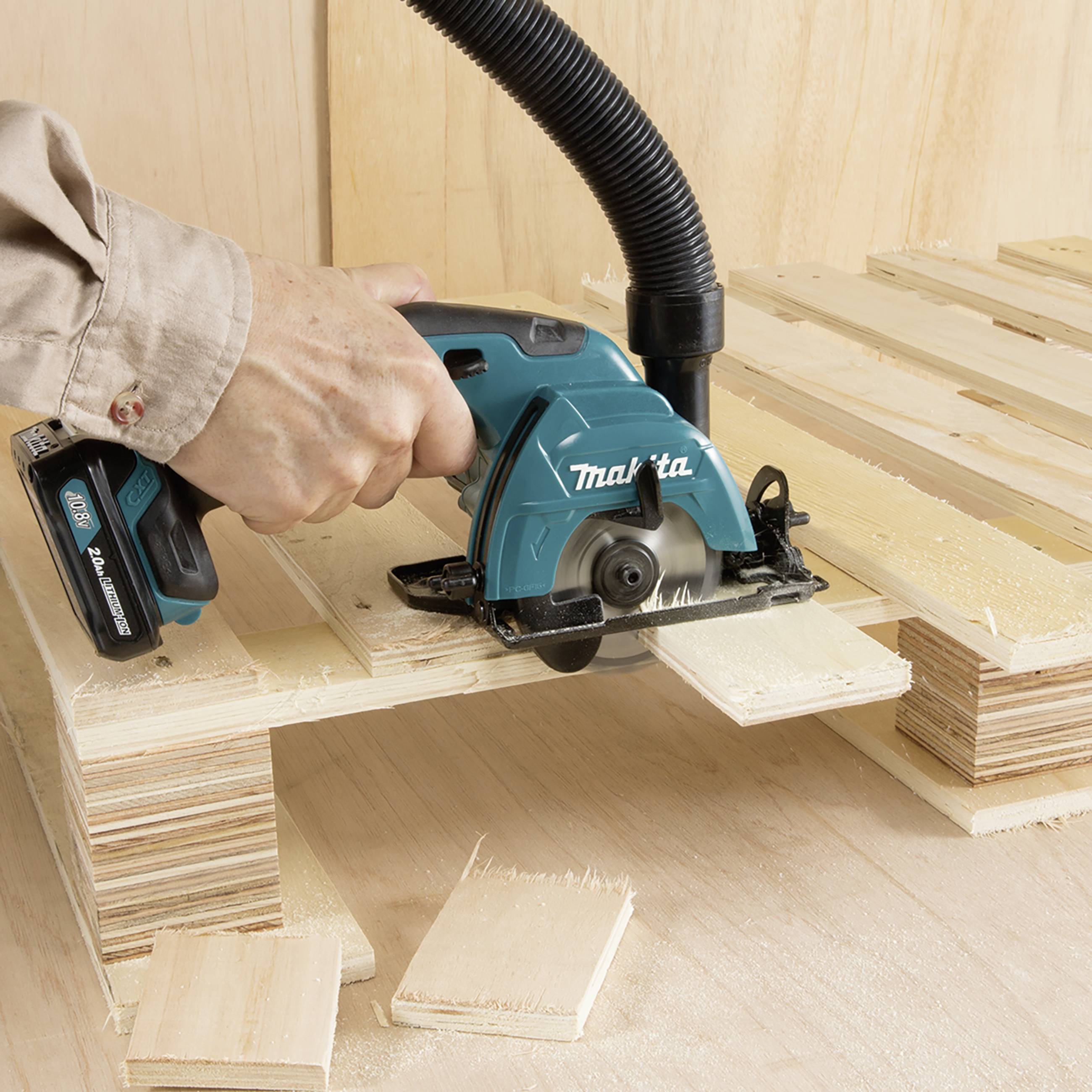 Ein Arbeiter schneidet mit einer Handkreissäge Holzplatten. Sägespäne fliegen, während die Maschine das Holz bearbeitet.