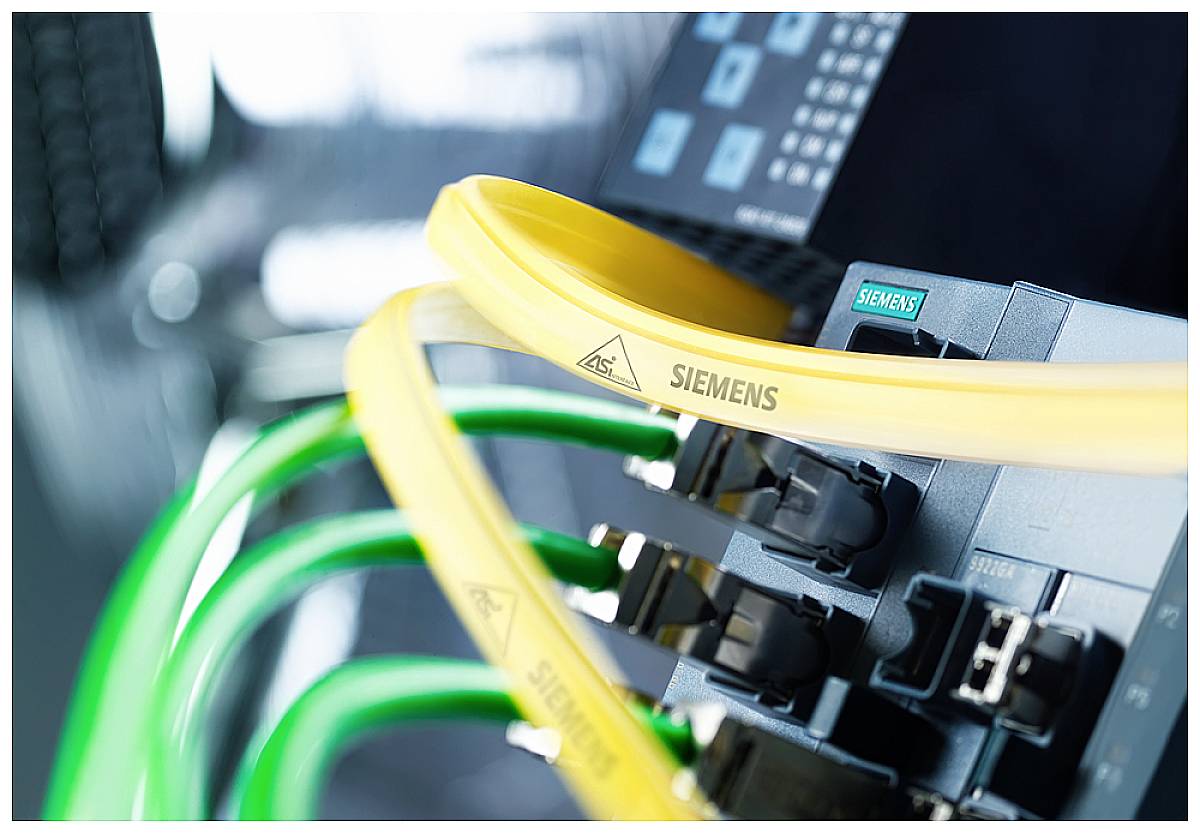 Gelbe und grüne Kabel sind an ein Siemens-Gerät angeschlossen, das Kontrollanzeigen zeigt. Fokus auf Vernetzung und Technologie.