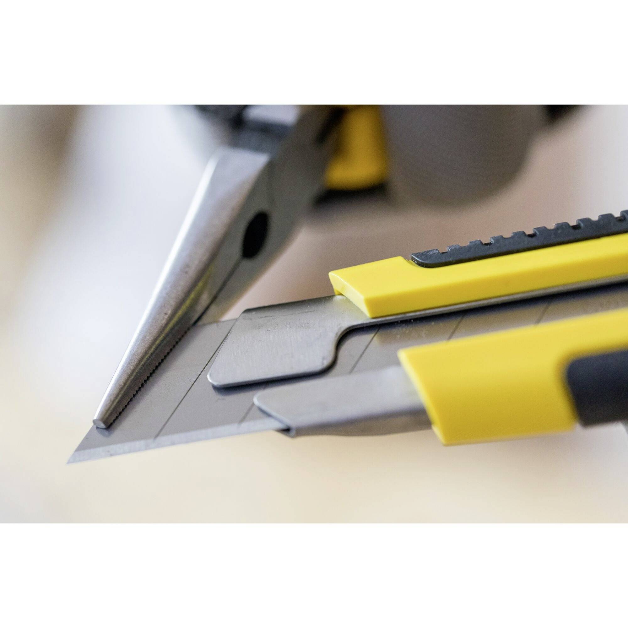Gelber Cutter und Zange liegen auf dem Tisch, scharf fokussiert, Hintergrund unscharf. Sie symbolisieren Werkzeuge und Handwerksarbeit.