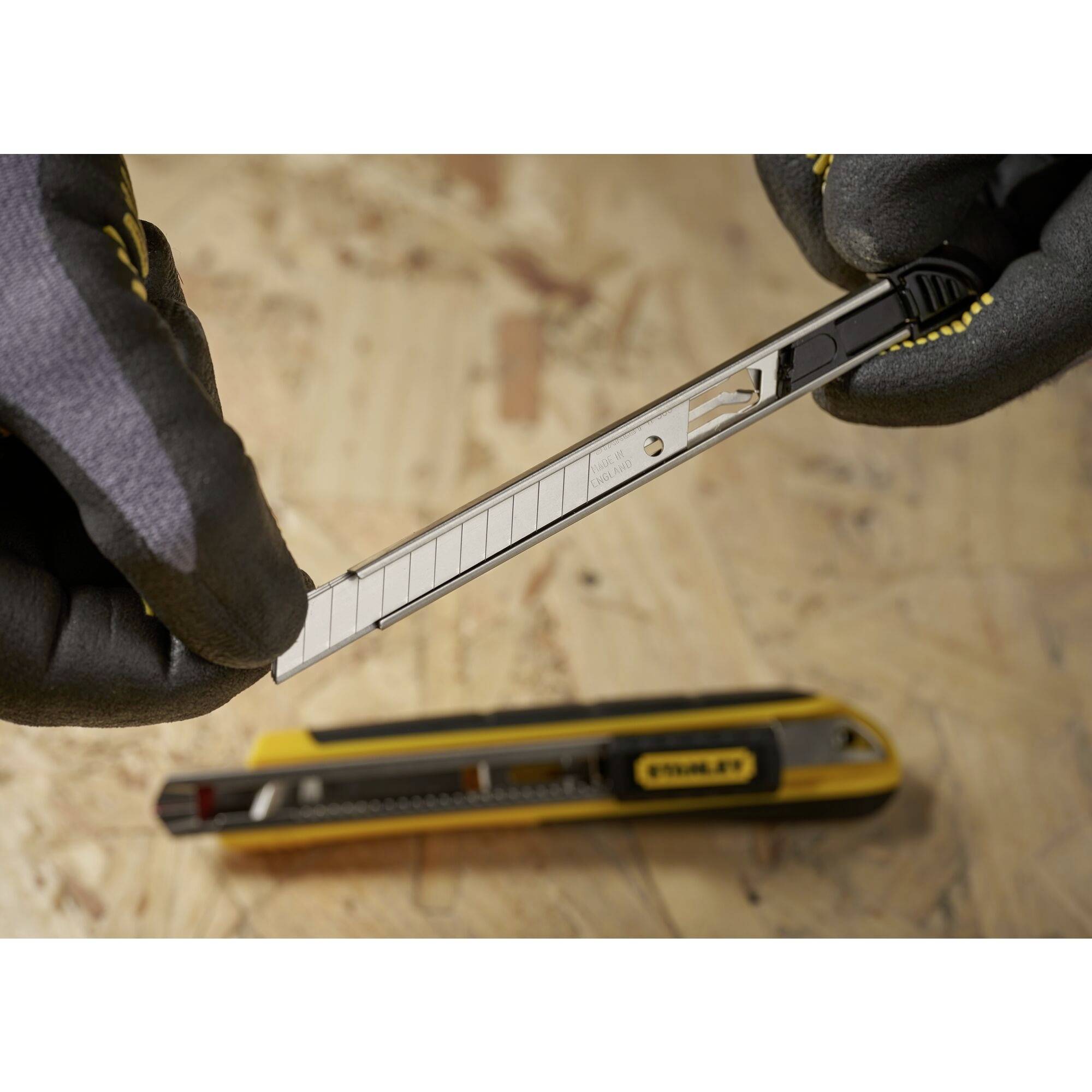 Ein Handschneider mit mehreren Klingen wird von einer Person in Schutzhandschuhen gehalten. Ein gelber Cutter liegt im Hintergrund.