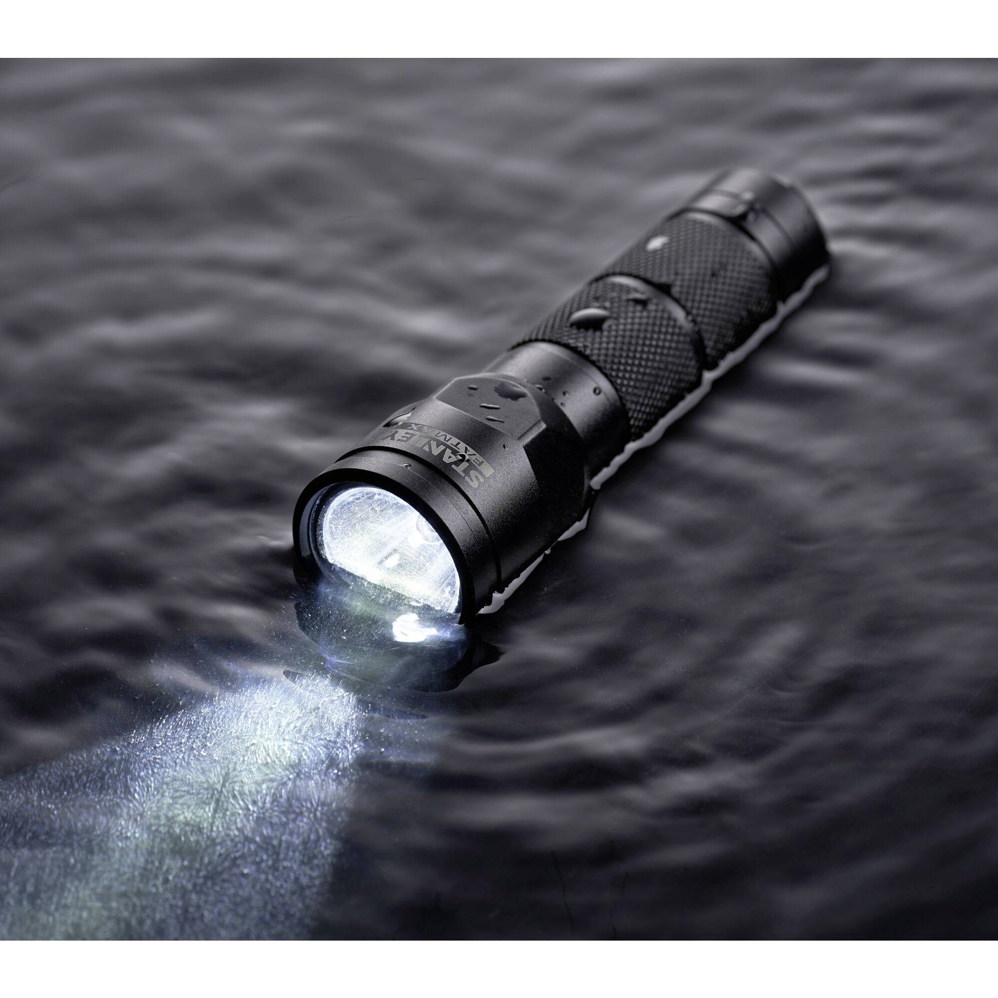 Eine wasserdichte Taschenlampe schwimmt und leuchtet auf der Oberfläche eines dunklen Gewässers.
