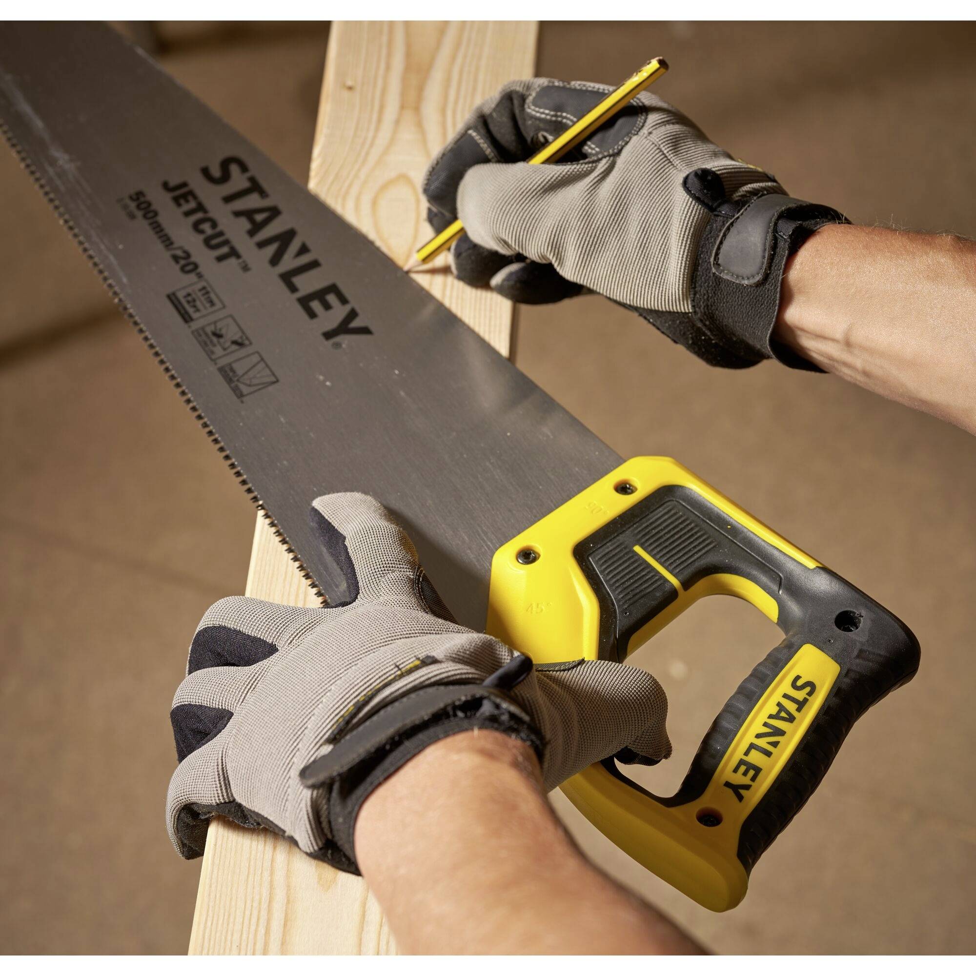 Eine Person mit Arbeitshandschuhen sägt mit einer Stanley-Säge ein Holzbrett, während sie mit einem Bleistift eine Markierung macht.
