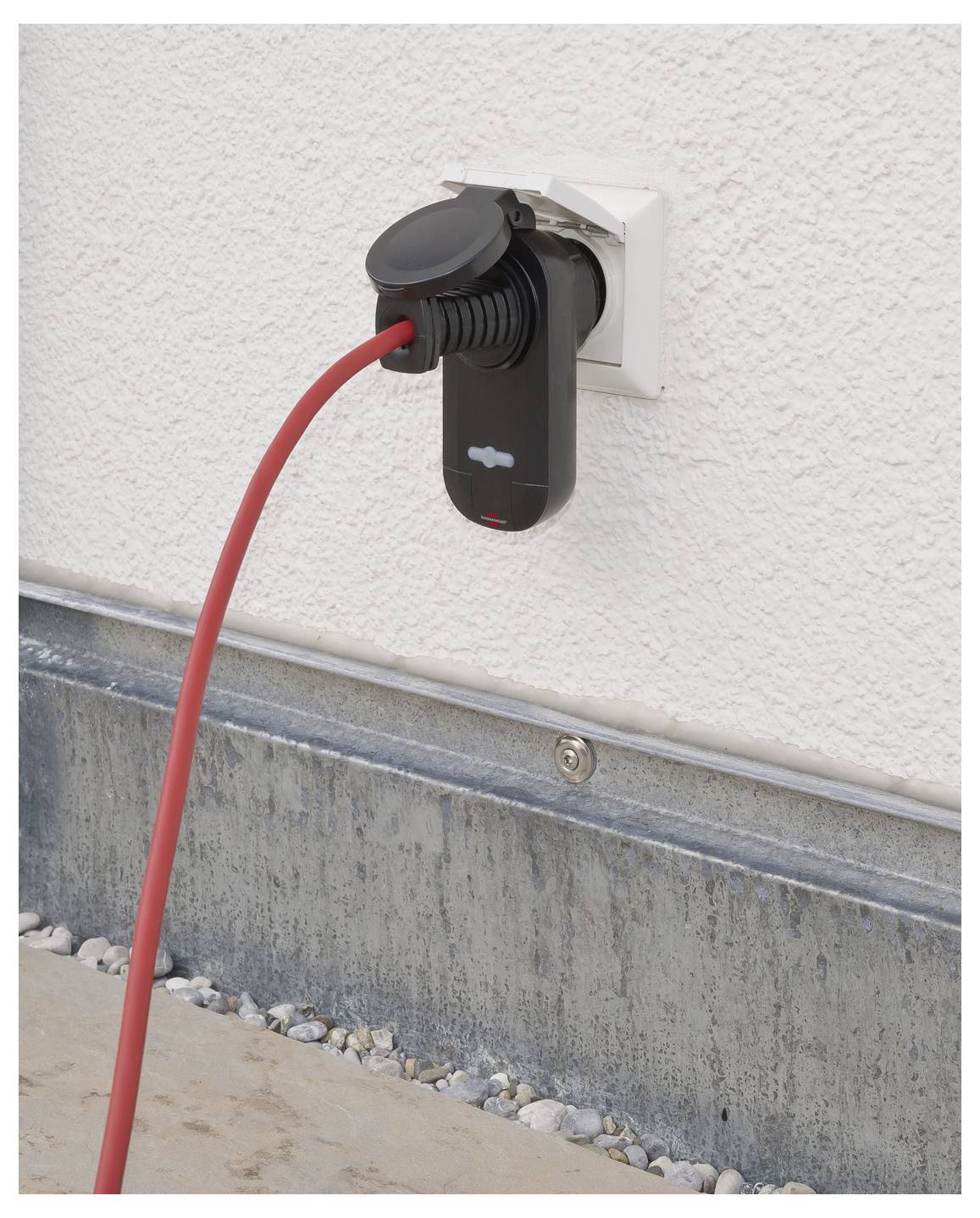 Rotes Elektroladekabel eingesteckt in eine an der Außenwand eines Hauses montierte Ladestation.