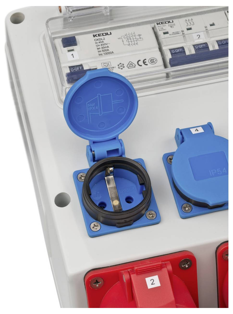 Elektroschalttafel mit blauen und roten industriellen Steckdosen und Schutzschaltern hinter einer transparenten Abdeckung.