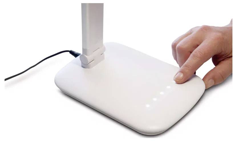 Eine Hand berührt ein weißes Gerät mit LED-Anzeigen, möglicherweise einen Stromschalter, auf einem modernen, minimalistischen Design, das durch ein Kabel verbunden ist.