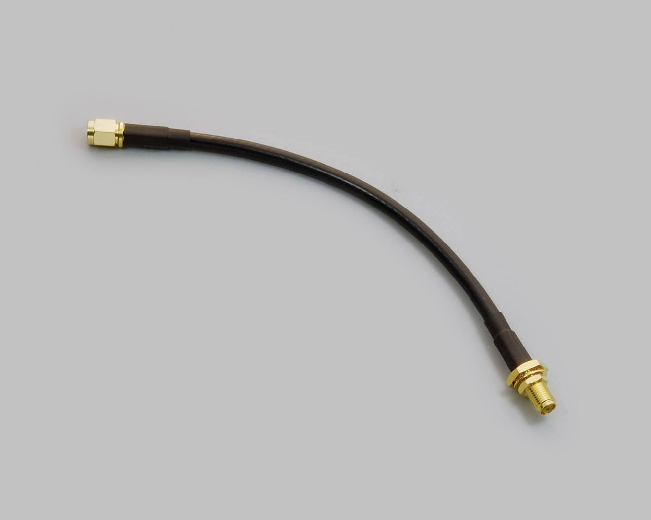 Ein Koaxialkabel mit goldfarbenen Steckern an beiden Enden auf grauem Hintergrund.