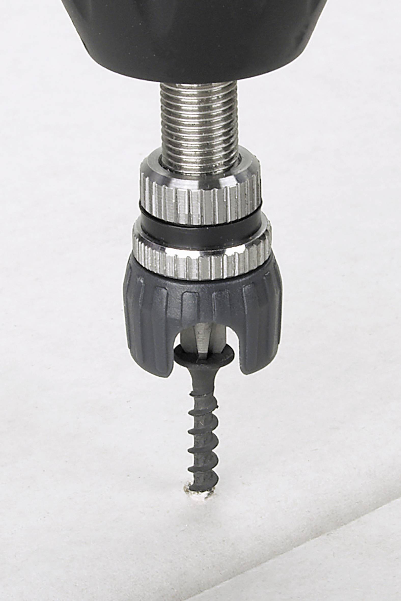 Ein Schraubendreher dreht eine schwarze Schraube in weißes Material.