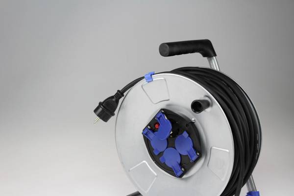 Eine Kabeltrommel mit schwarzem Kabel auf einem Ständer. Das Kabel hat einen EU-Stecker; die Trommel hat mehrere blaue Steckdosen.