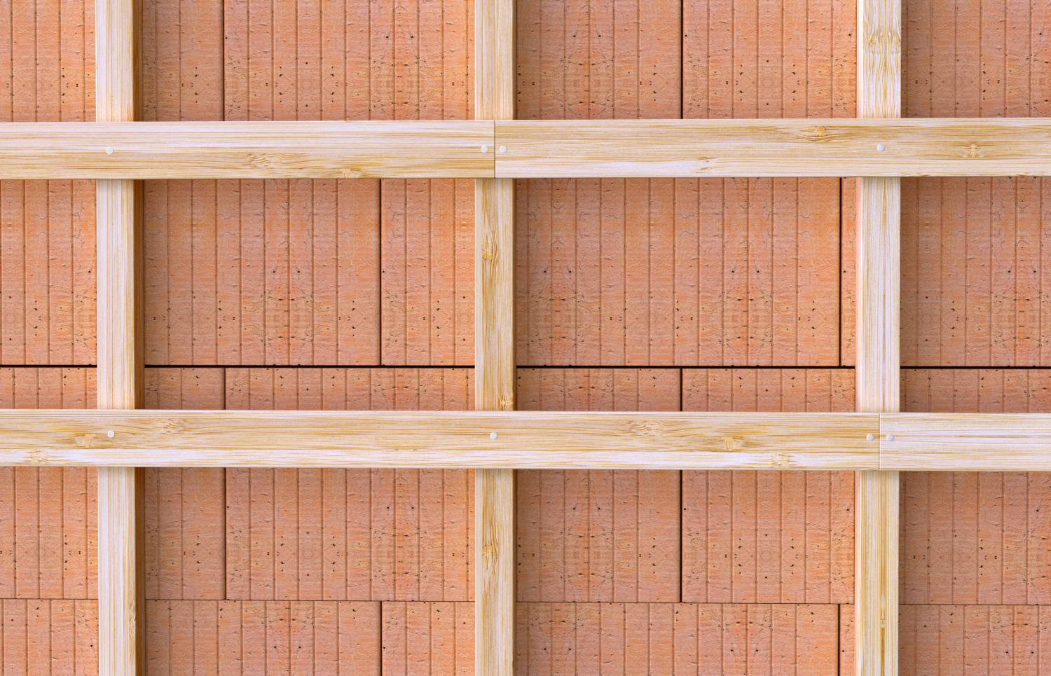 Nahaufnahme eines Holzgitterzauns mit hellgefleckten horizontalen und vertikalen Latten vor einer rötlichen Backsteinmauer.