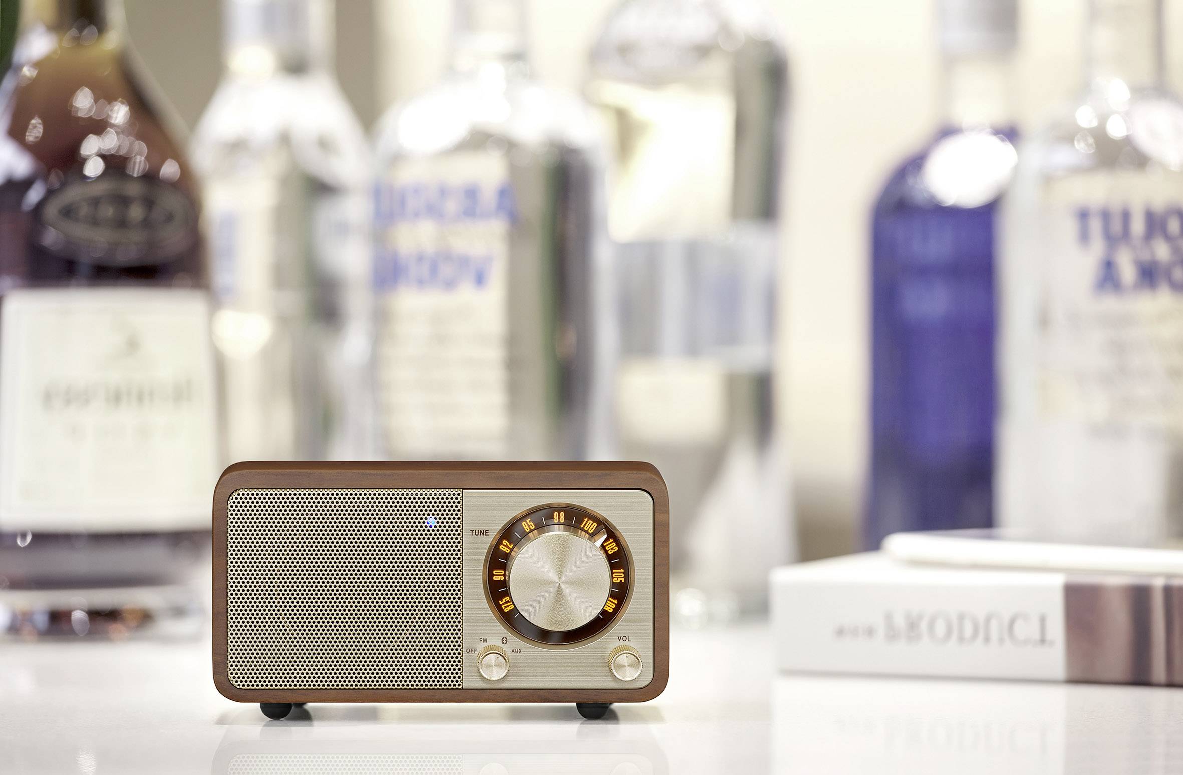 Brauner Retro-Radiowecker mit Drehknopf im Vordergrund, umgeben von unscharfen Flaschen im Hintergrund auf einem Tisch.