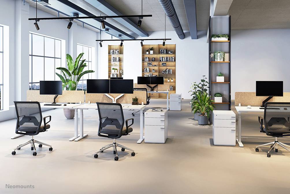 Ein modernes, gut beleuchtetes Büro mit mehreren Schreibtischen, Bürostühlen und Computermonitoren; Pflanzen dekorieren den Raum.