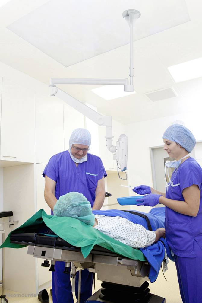 Ein Patient liegt auf einem OP-Tisch, während zwei Chirurgen in blauen Kitteln und OP-Mützen Vorbereitungen im Operationssaal treffen.