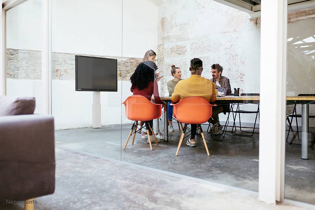 Mehrere Personen sitzen in einem hellen, modernen Besprechungsraum an einem Tisch. Sie diskutieren und arbeiten gemeinsam an einem Projekt.