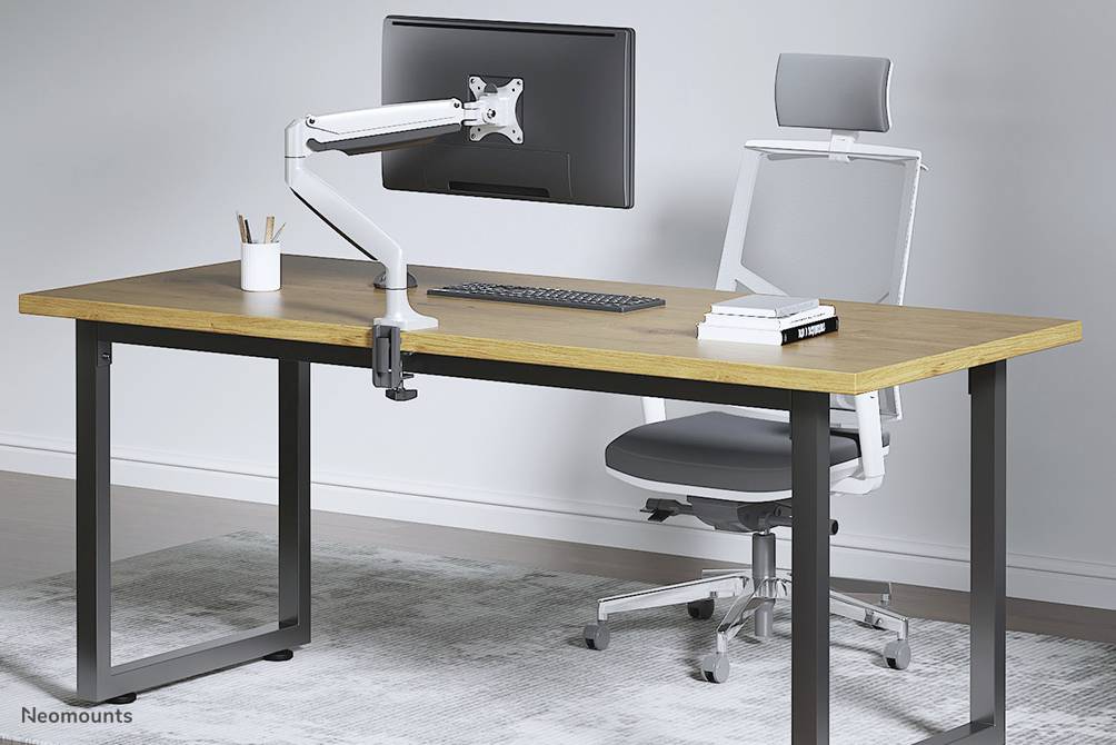 Ein moderner Schreibtisch mit Holzplatte, Bildschirmhalterung und ergonomischem Stuhl auf einem Teppich. Bürobedarf ist auf dem Tisch.