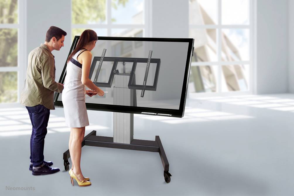 Ein Mann und eine Frau interagieren mit einem großen Touchscreen, der auf einem Rollständer montiert ist, in einem hellen Raum.