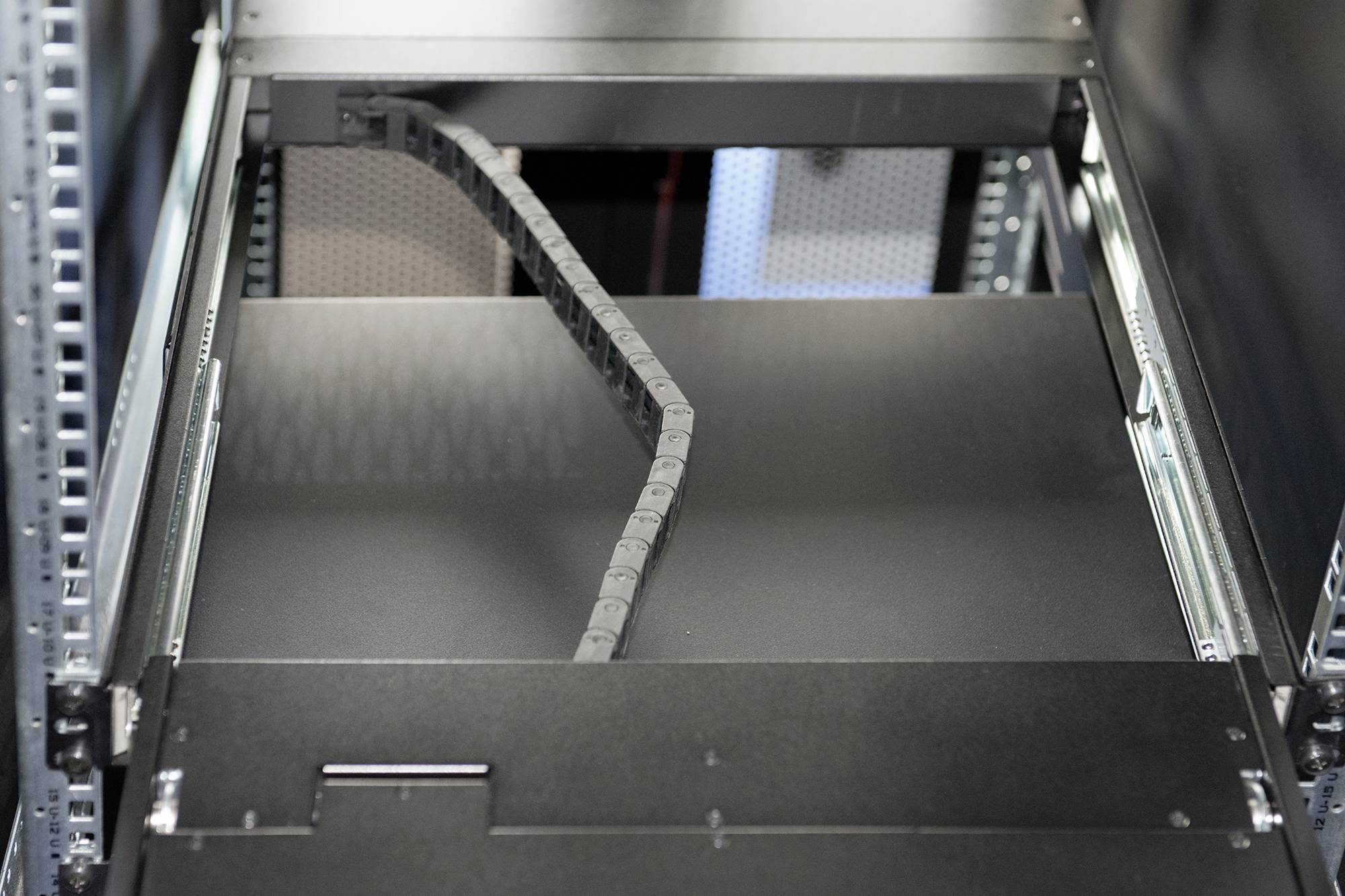 Ein leeres, offenes Server-Rack in einem Rechenzentrum mit sichtbaren Schienen und Kabeln.