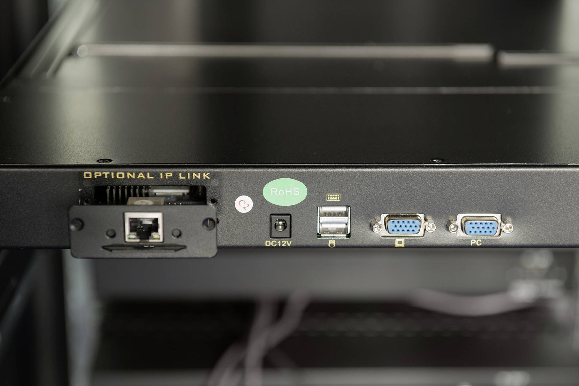 Rückseite eines technischen Geräts mit mehreren Anschlüssen: Ethernet, USB, VGA und ein Netzanschluss. Grünen 'RoHS'-Aufkleber sichtbar.