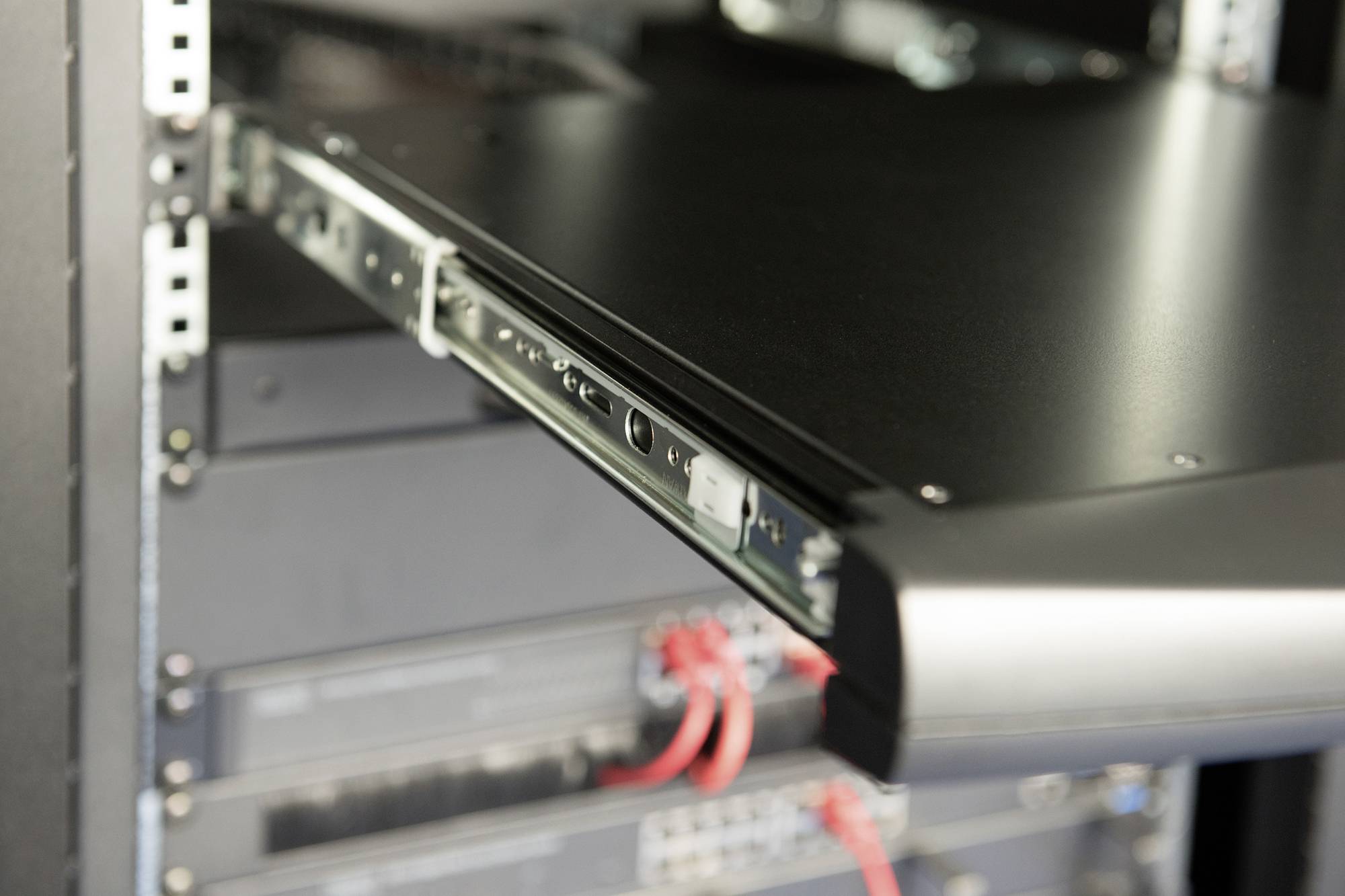 Ein geöffneter Server-Schrank zeigt Rack-Server mit angeschlossenen Kabeln. Hauptsächlich schwarze Hardware ist sichtbar.
