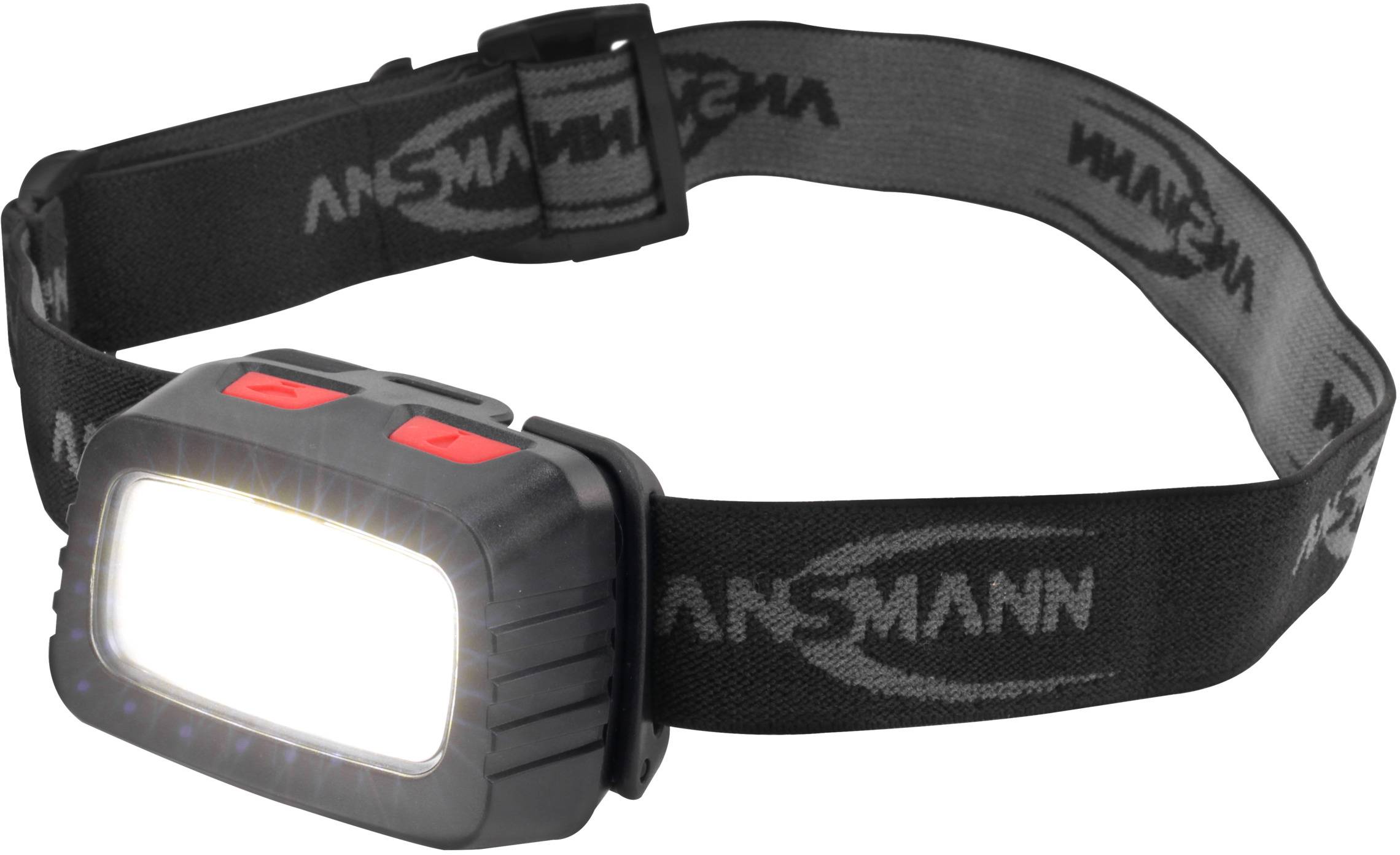Eine schwarze Stirnlampe mit grauem Band und rotem Schalter auf der Oberseite, die hell leuchtet. Auf dem Band steht 'ANSMANN'.