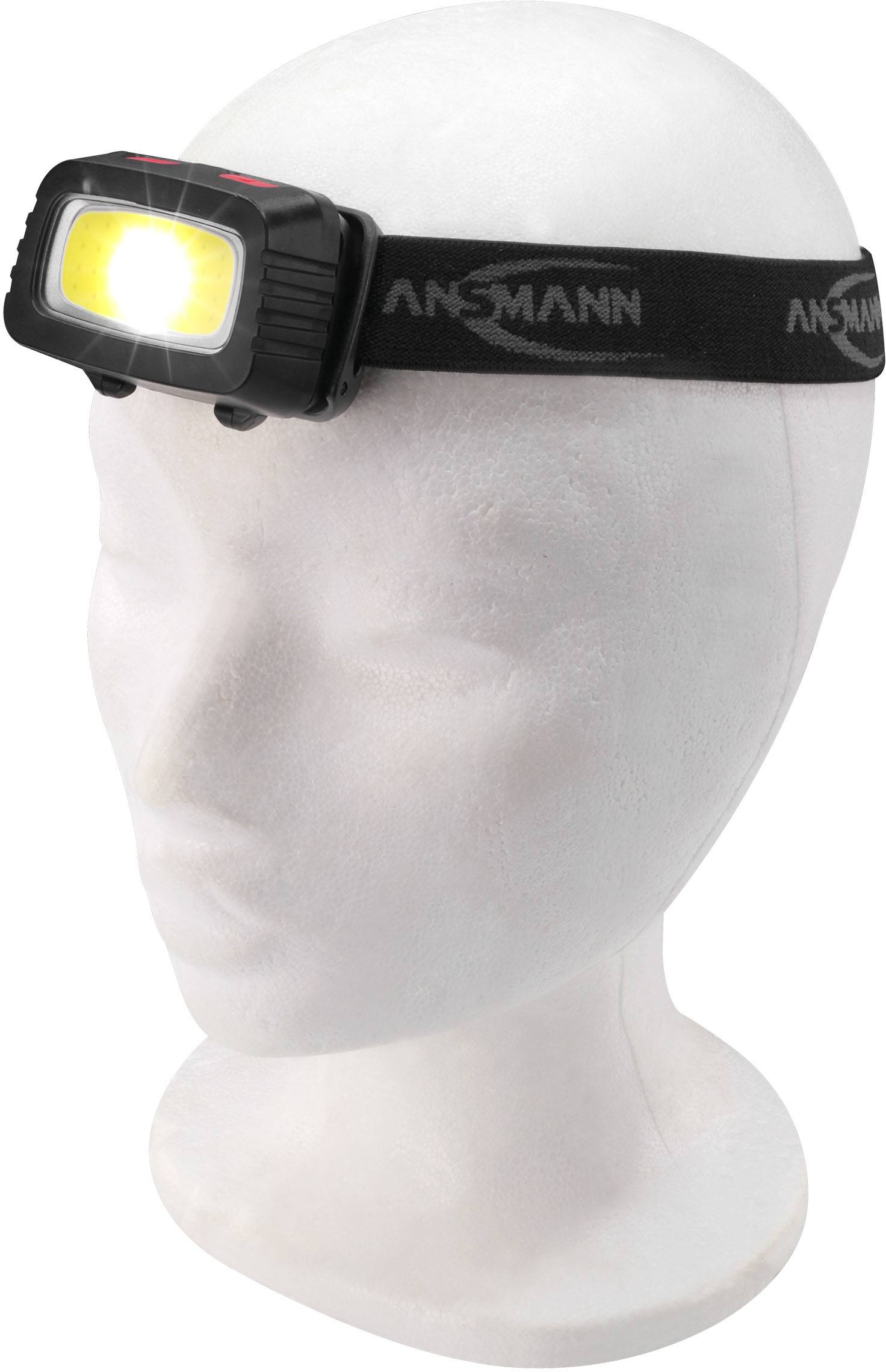 Kopfmodell mit angeleuchteter Stirnlampe, befestigt an einem elastischen Band mit 'Ansmann'-Logo.