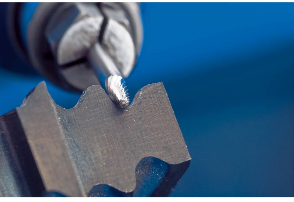 Ein Fräswerkzeug bearbeitet die Kante eines Metallstücks. Der Fokus liegt auf dem Schneidvorgang und der glatten Metalloberfläche.