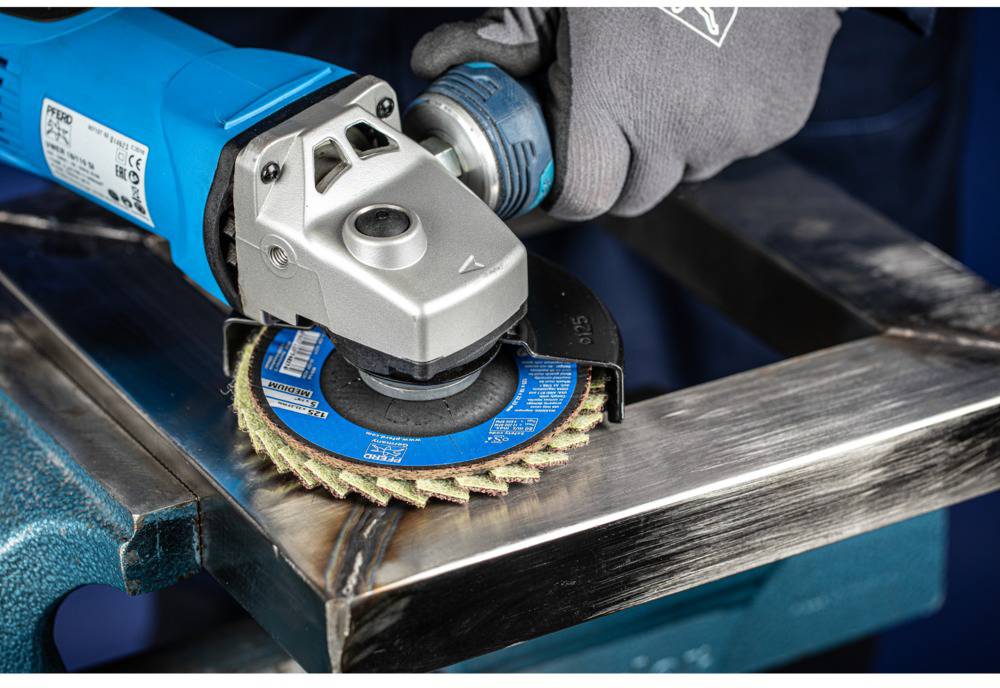 Eine Person schleift eine Metallecke mit einer blauen Winkelschleifmaschine und einer Schleifscheibe.