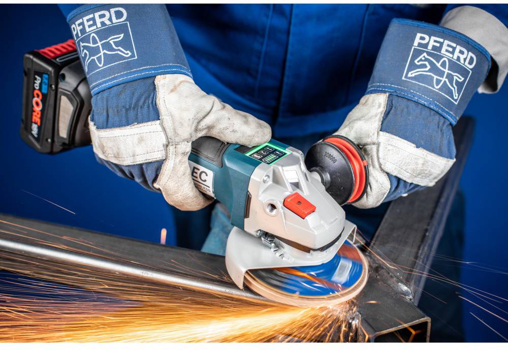 Person in Schutzkleidung schleift Metall mit einer Winkelschleifmaschine. Funken sprühen während des Schleifprozesses.