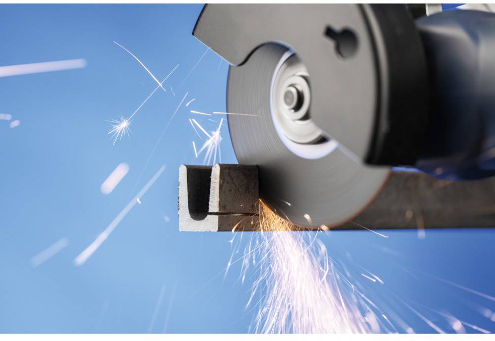 Ein Winkelschleifer schneidet durch ein Metallstück, Funken fliegen.