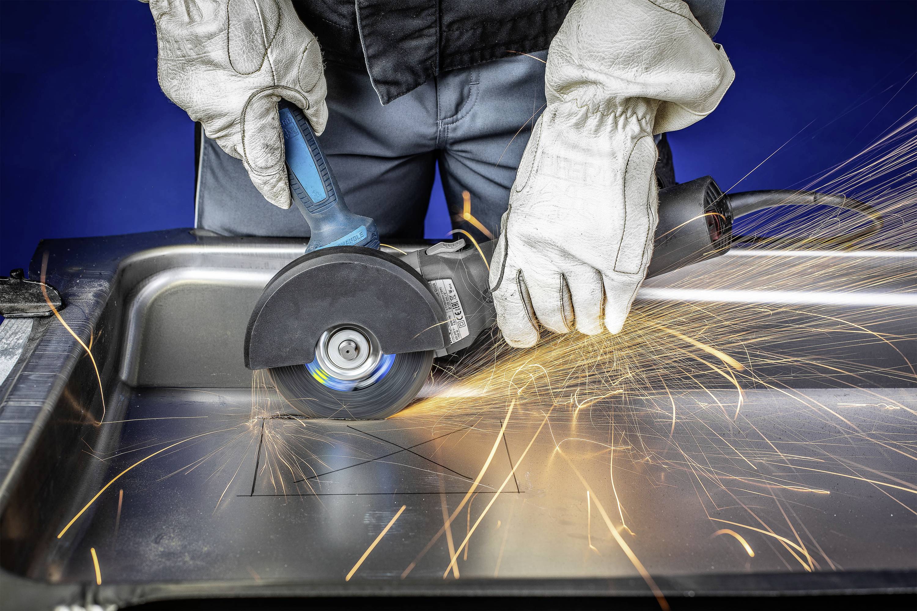 Eine Person schneidet mit einem Winkelschleifer ein Metallblech. Funken sprühen vom Kontaktpunkt aus.