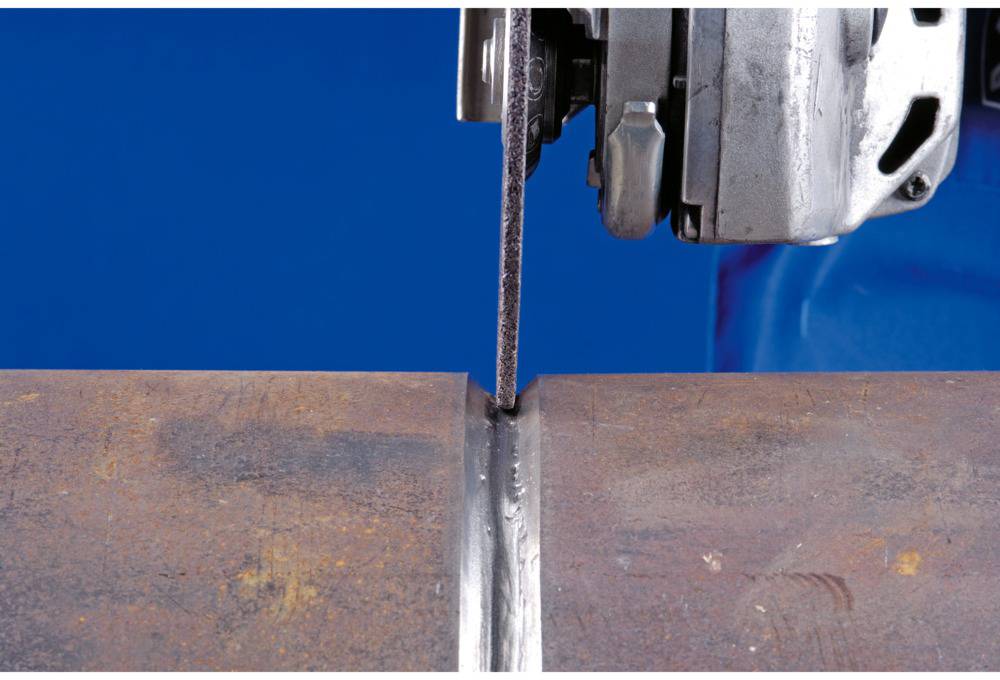 Eine Metallsäge schneidet durch ein dickes Stück Metall vor einem blauen Hintergrund.