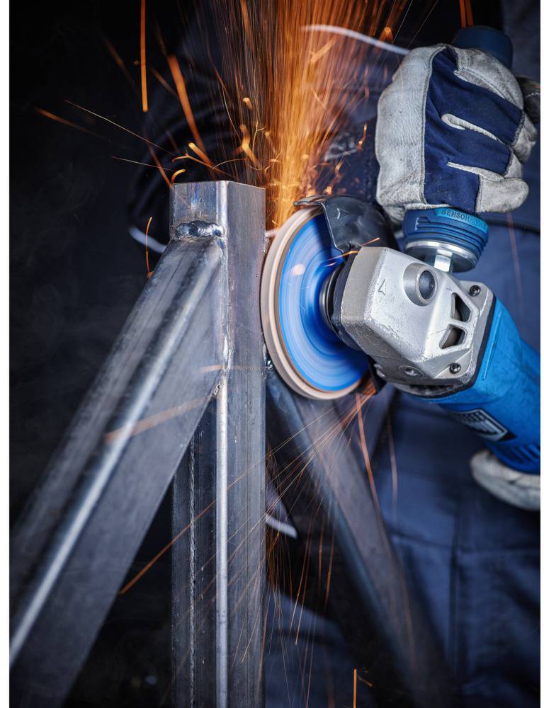 Ein Arbeiter schleift ein Metallrohr mit einem Winkelschleifer. Funken fliegen in alle Richtungen, während das Werkzeug das Metall bearbeitet.