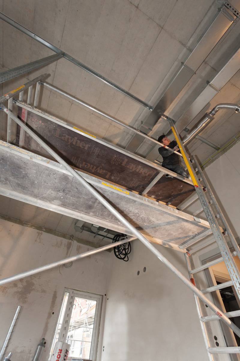 Bauarbeiter auf einem Gerüst arbeitet an der Decke einer unfertigen Baustelle.