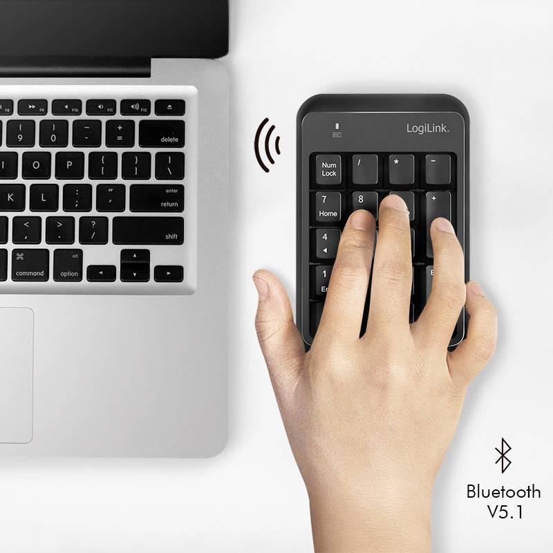 Eine Hand benutzt ein drahtloses Zahlenfeld neben einem Laptop. Das Zahlenfeld verbindet sich per Bluetooth, Version 5.1.