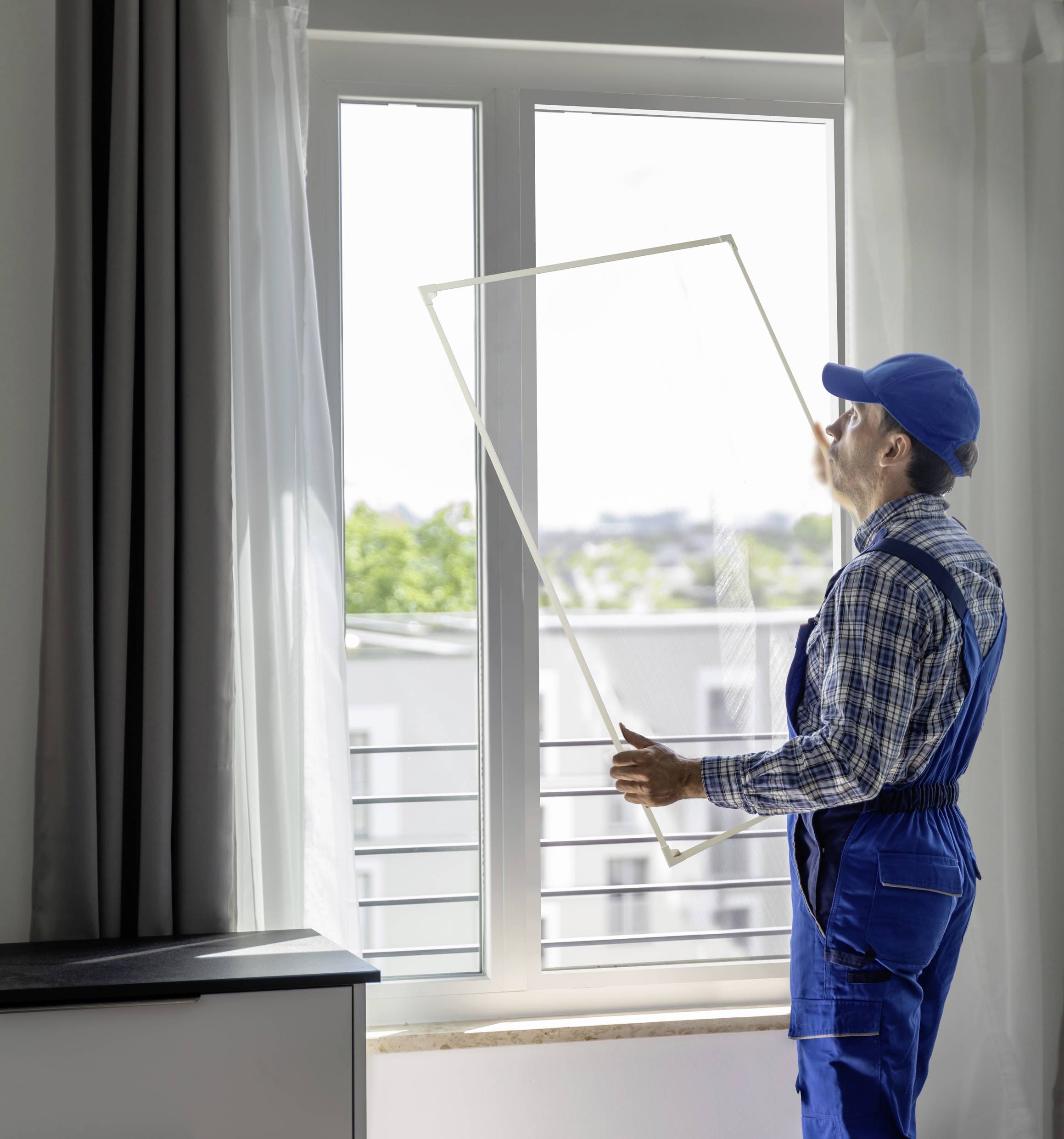 Eine Person in Arbeitskleidung ersetzt ein Fenster in einem modernen Raum. Tageslicht fällt durch das Fenster.