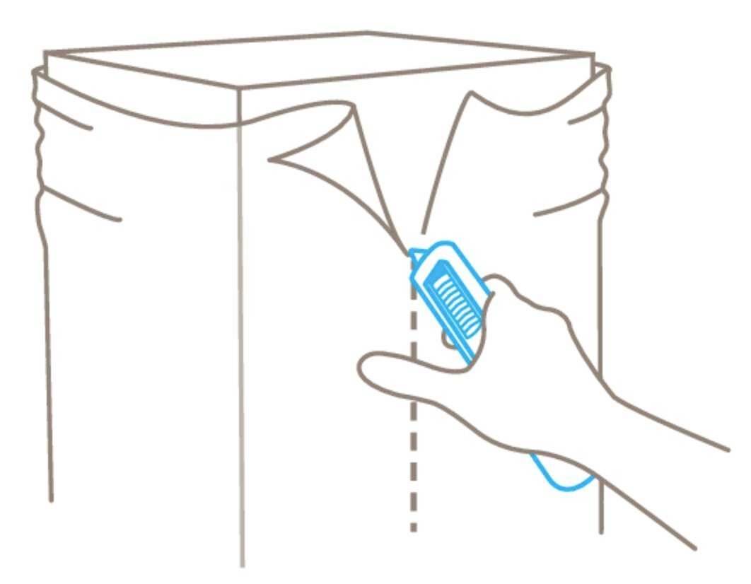 Eine Hand öffnet mit einem Cutter-Messer die obere Naht eines Papiersacks.