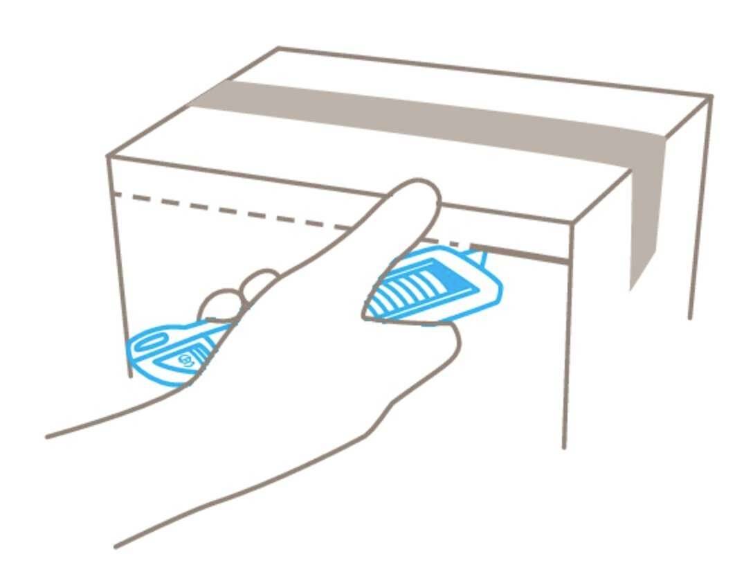 Eine Hand steckt ein Abholschein in einen Schlitz eines Pakets an einer Theke ein.