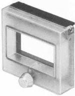 Ein flaches, rechteckiges Metallobjekt mit einem zentralen rechteckigen Hohlraum und einem hervorstehenden Drehknopf unten.