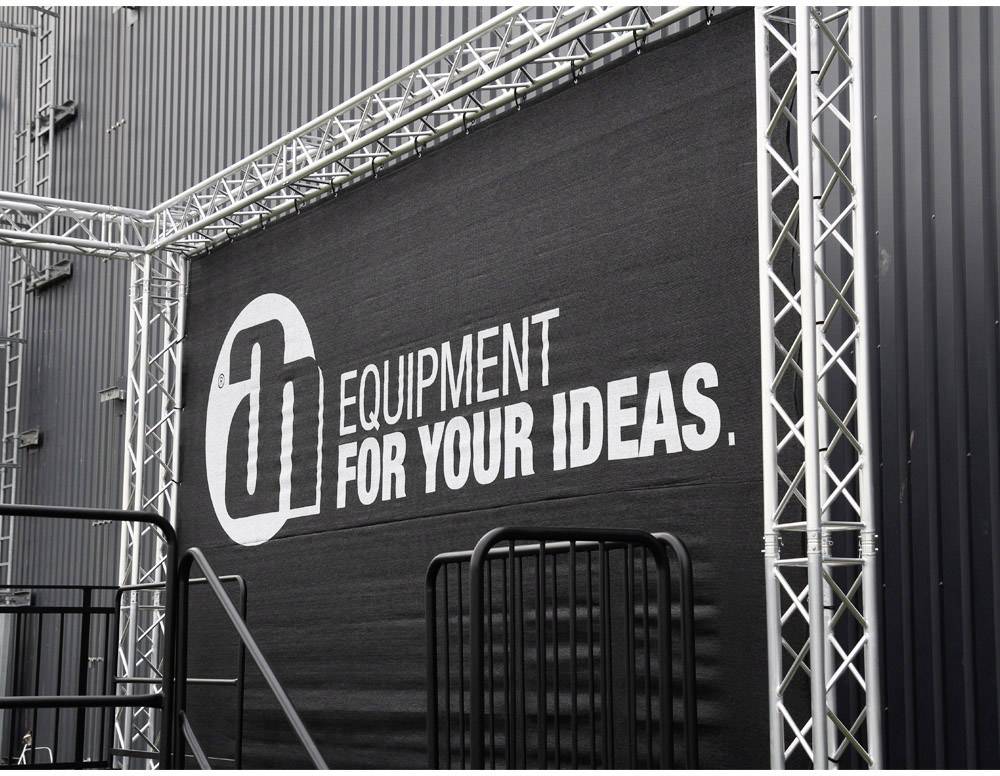 Schwarzes Banner mit weißem Text: 'equipment for your ideas.' im Hintergrund einer Metallgerüstrahmenstruktur.