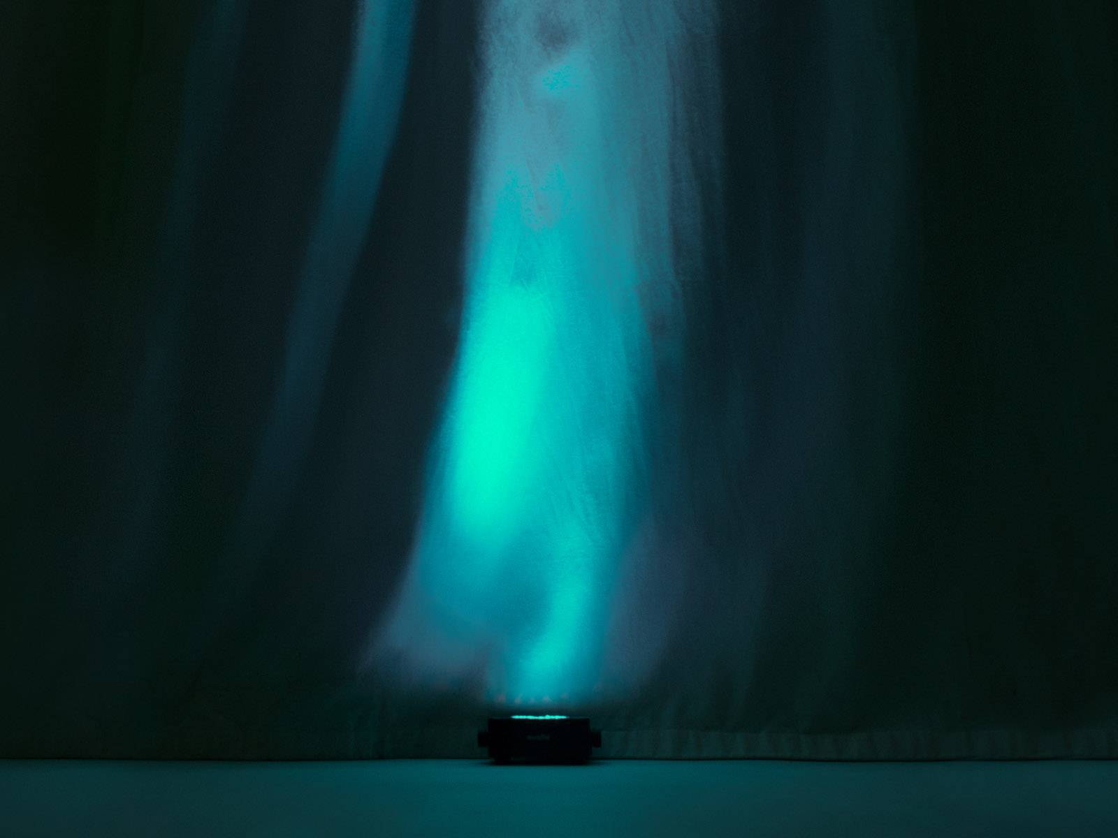Ein blau-grünes Licht strahlt nach oben und erzeugt eine geheimnisvolle, stimmungsvolle Atmosphäre auf einem dunklen Hintergrund.