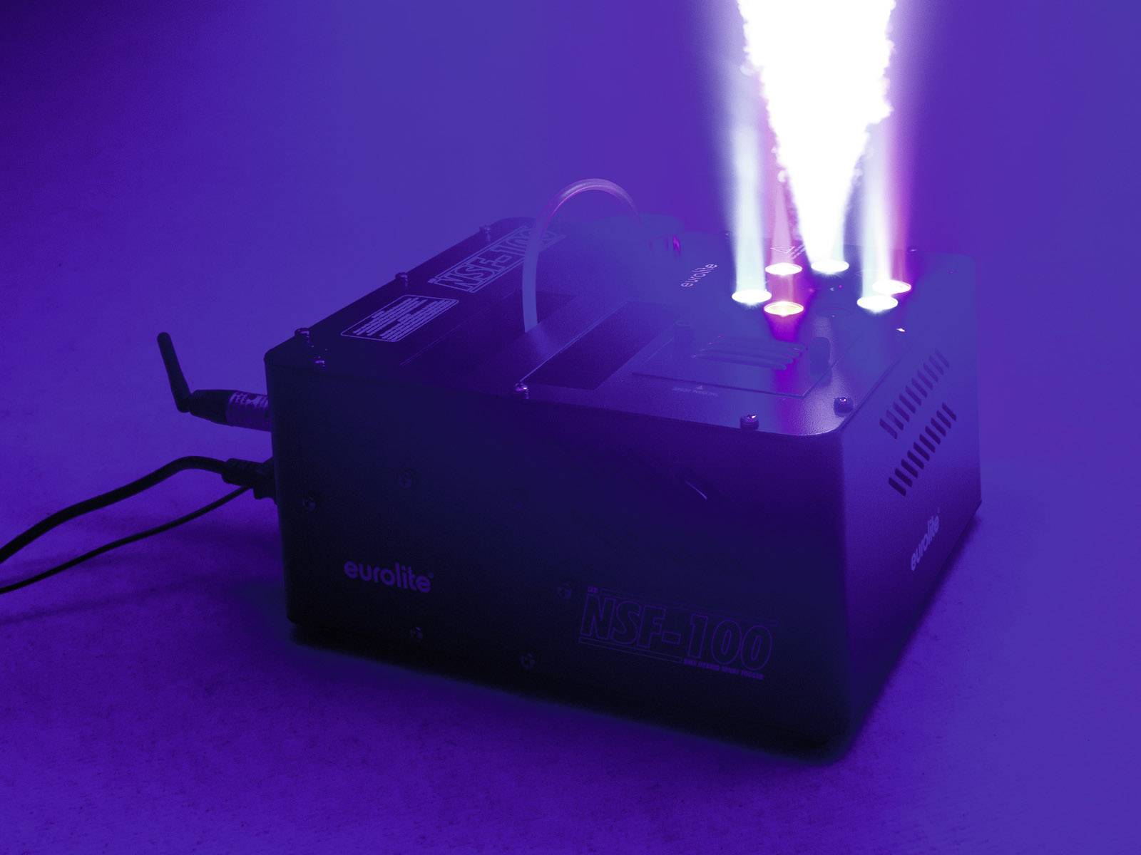 Nebelmaschine emittiert dichten Dampfströme unter blauem Licht. Gerät zeigt Marke 'Eurolite' und Modell 'NSF-1100'. Entstehung von Spezialeffekten.