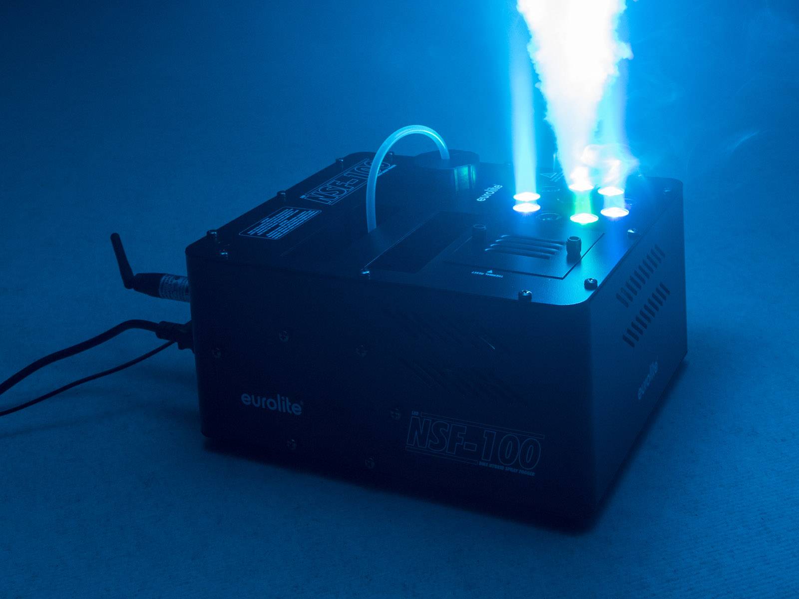 Nebelmaschine sprüht blauen Nebel in einem dunklen Raum. Lichtstrahlen und Rauch erzeugen eine futuristische Atmosphäre.