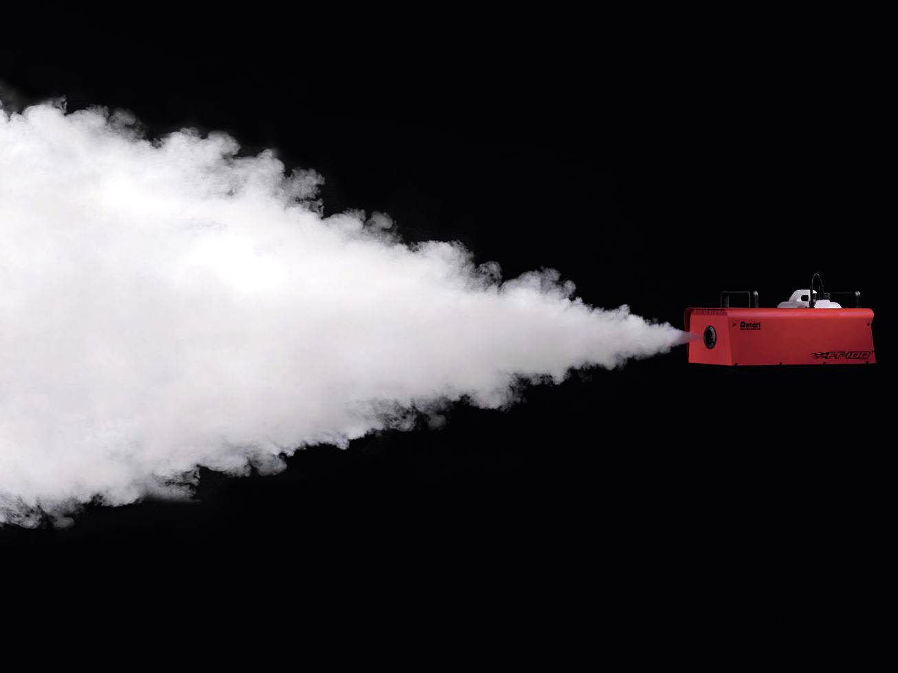 Eine rote Maschine stößt einen weißen Rauchstrahl aus, der sich gegen einen schwarzen Hintergrund ausbreitet.