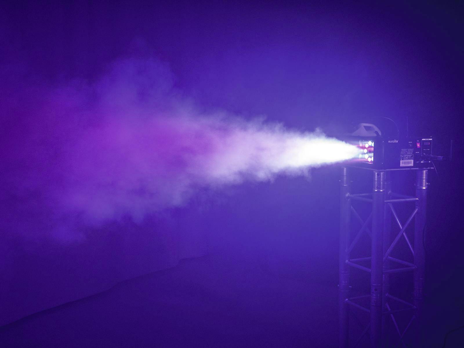 Ein Projektor strahlt einen Lichtstrahl mit Nebel, der in verschiedenen Farben schimmert, auf einem dunklen Hintergrund aus.