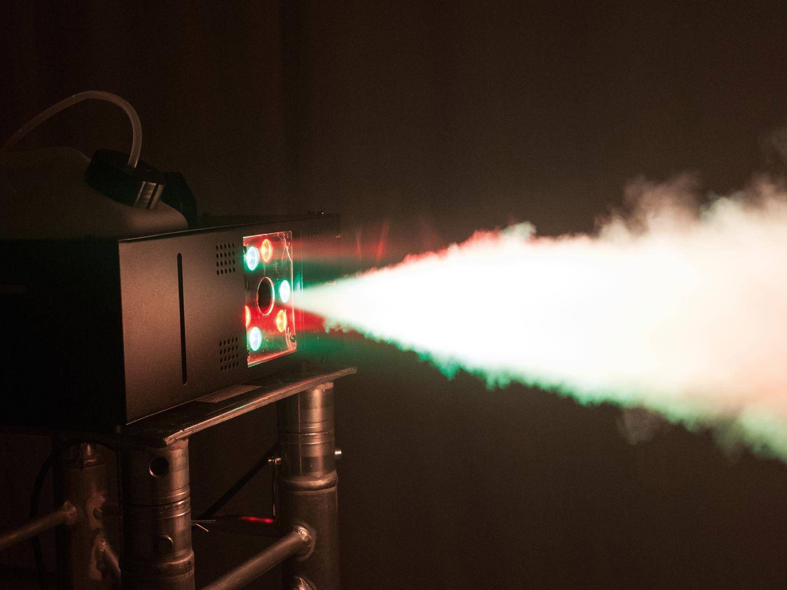 Ein Rauchgerät projiziert einen starken, bunten Lichtstrahl durch den Nebel, was bei Bühnenauftritten faszinierende Effekte erzeugt.