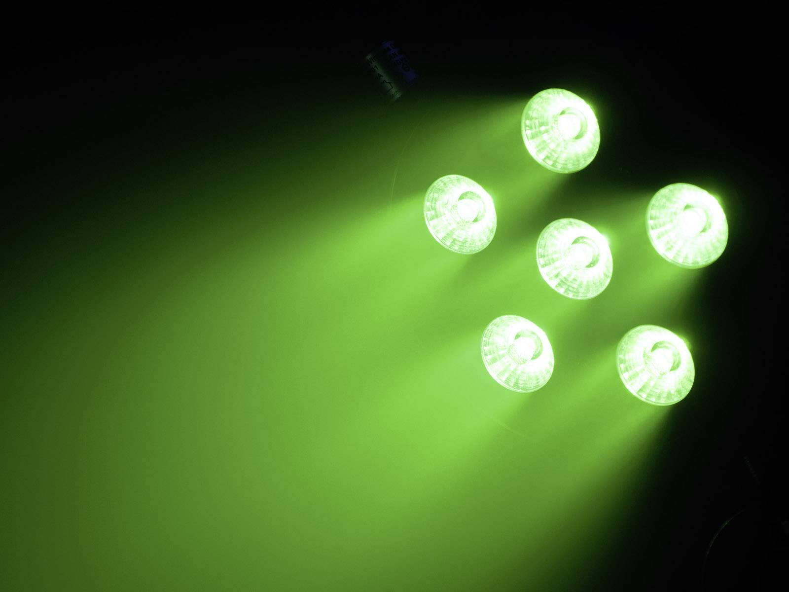 Sechs grüne Lichter in einem dunklen Raum, die nach unten leuchten, erzeugen leuchtende Strahlen und eine futuristische Atmosphäre.