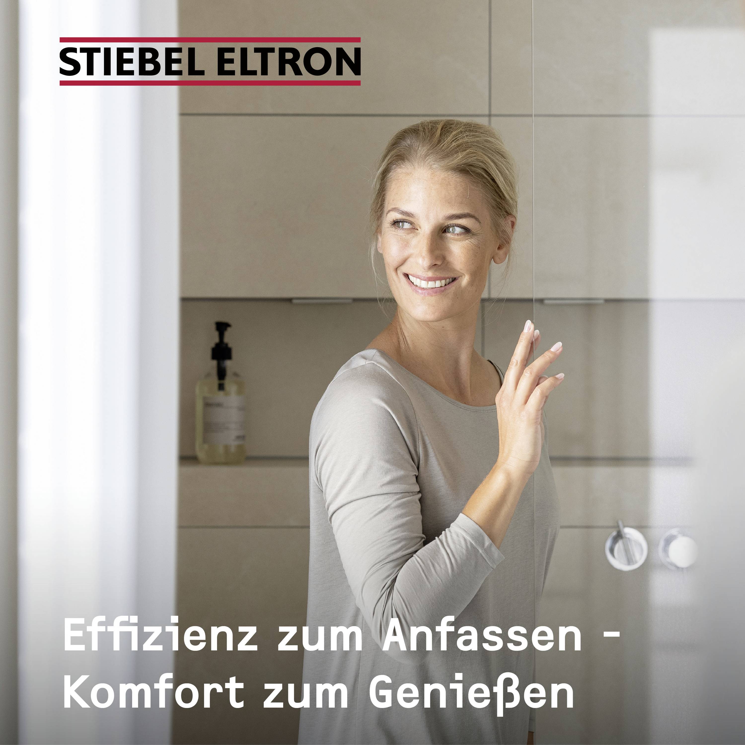 Frau steht lächelnd in einem modernen Badezimmer. Text: 'Effizienz zum Anfassen - Komfort zum Genießen'.