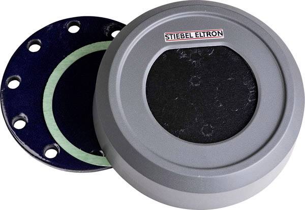 Grauer runder Deckel mit dem Aufdruck 'STIEBEL ELTRON' und eine schwarze Bauteilscheibe mit grünem Dichtungsring daneben.